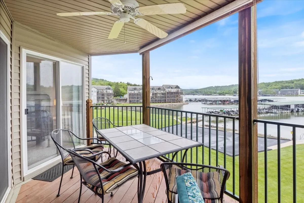 The image shows an outdoor dining table and comfortable seating overlooking a scenic marina. The serene setting is enhanced by the presence of boats and the tranquil water, inviting families to enjoy meals or relaxation in an outdoor, communal space.