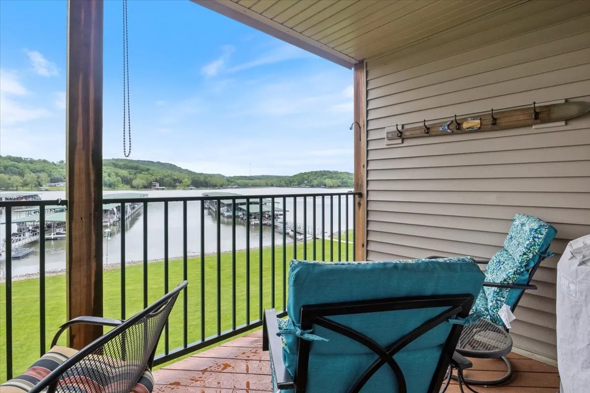 A scenic balcony with comfortable seating overlooking the water, a lush landscape, and the dock area. The setting invites morning coffee, sunset watching, or social gatherings with friends and family.