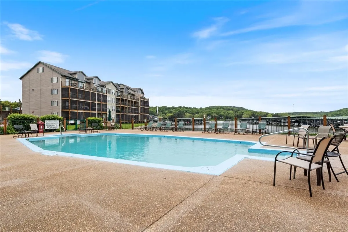 A sparkling swimming pool set against a waterfront backdrop with surrounding lounge chairs, inviting guests to enjoy a swim or relax by the water. The calm water beyond the pool enhances the sense of a lakeside retreat.