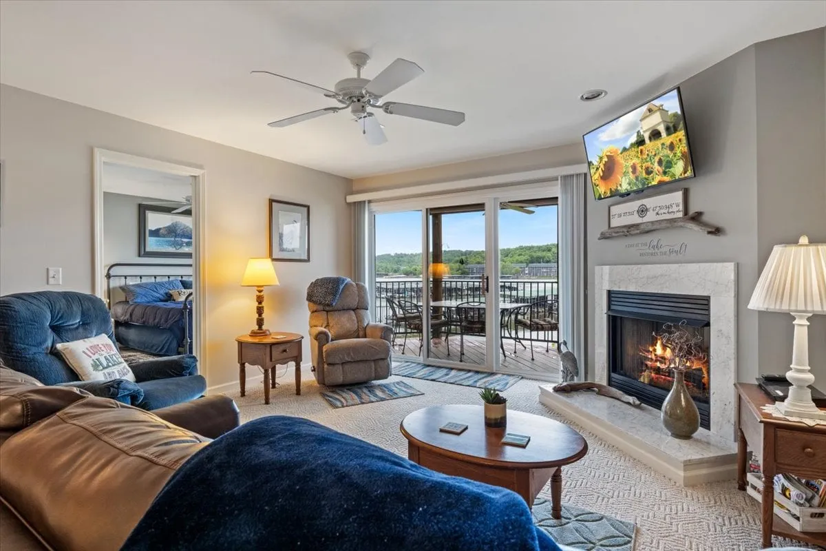 A welcoming living area with a fireplace, television, ample seating, and sliding doors that offer a clear view outside. The arrangement encourages relaxation while providing a glimpse of the natural landscape beyond.