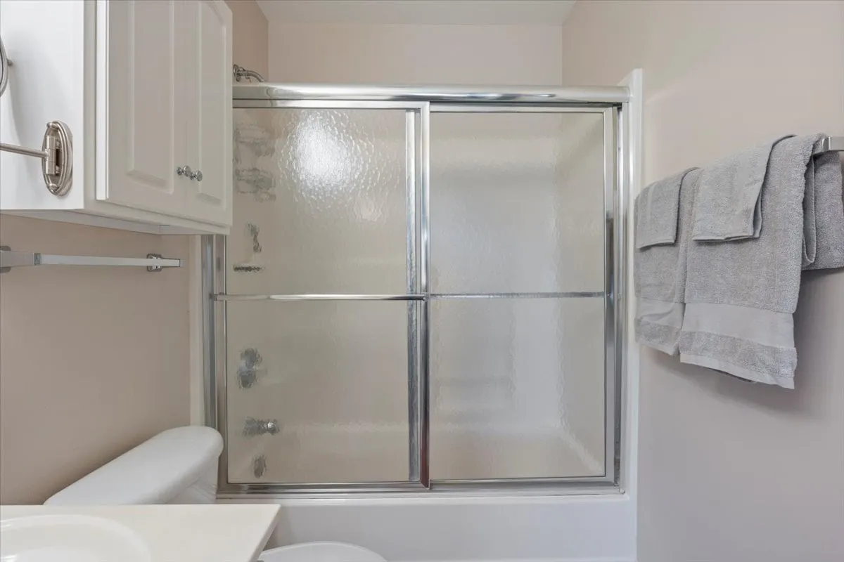 A serene bathroom scene featuring a shower enclosure, vanity countertop, and neatly arranged towels. The space is bright, clean, and inviting, with a focus on comfort and relaxation.